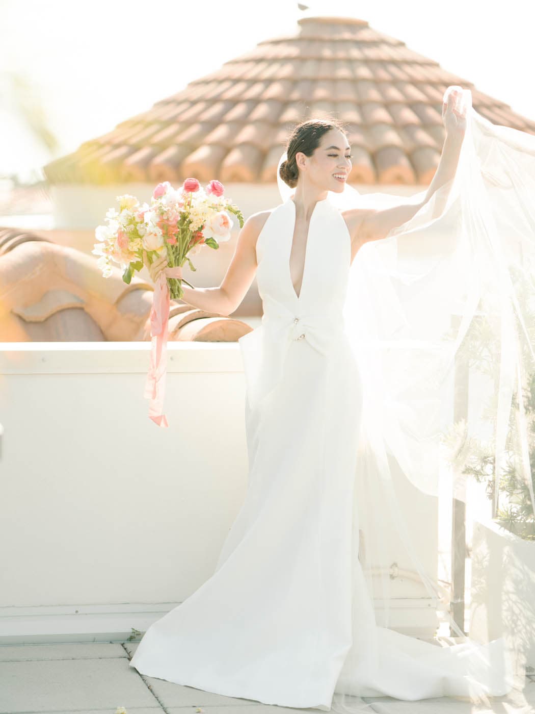 A bride holding a bouquet of flowers int eh sunshine at Inn on Fifth