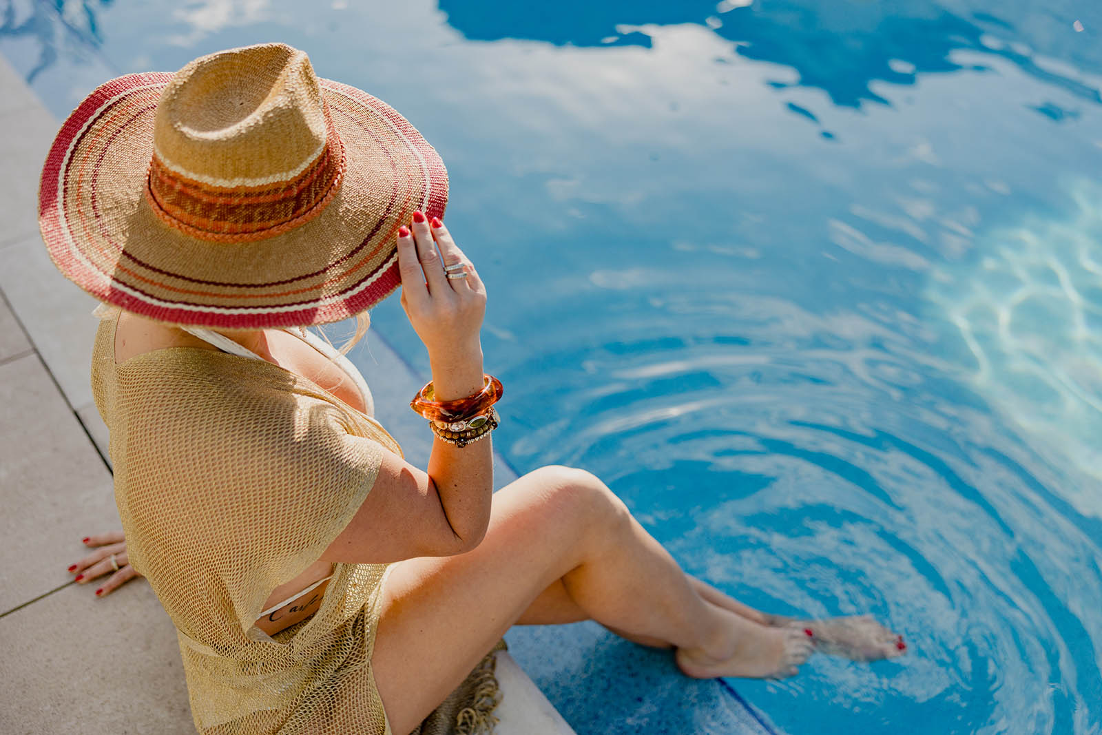 women sitting with feet in pool and sun hat